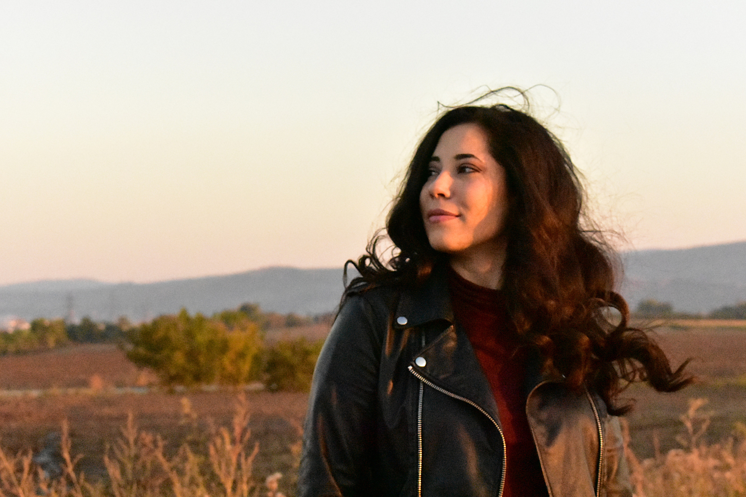 Woman Wearing Leather Jacket Standing in Grass Field